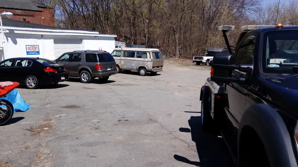 Vehicles and a tow truck parked in the lot outside the Guaranty Auto shop