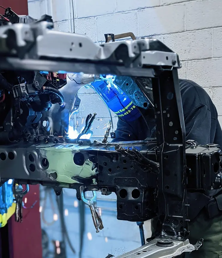 Welding on a vehicle frame section inside the Guaranty Auto body shop