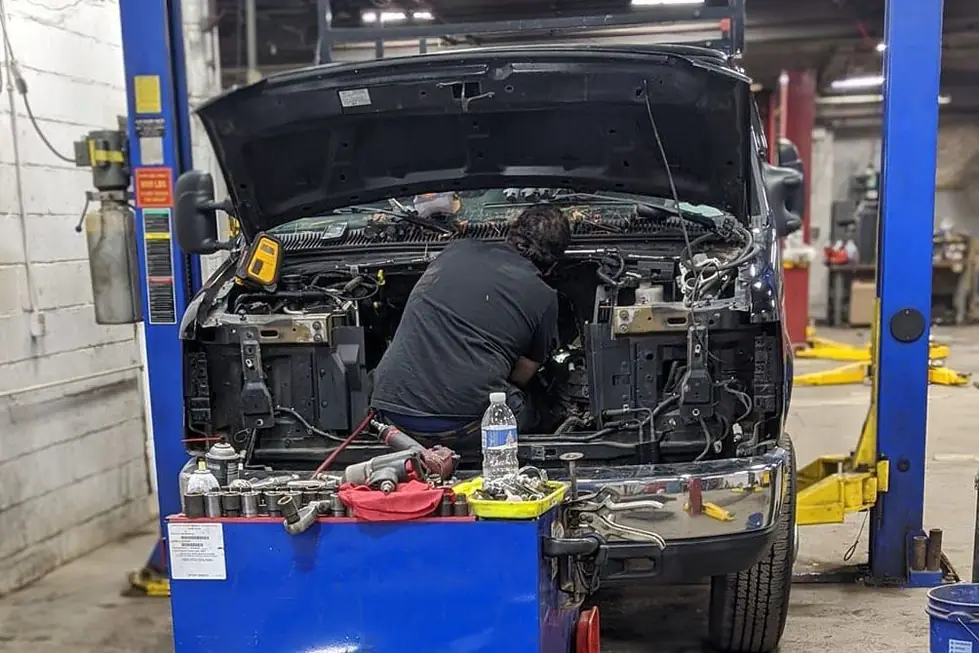 A Guaranty Auto technician working under the hood of a truck on a two-post lift